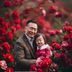 父亲抱着幼儿在洛阳牡丹花前合影，红色牡丹盛开背景下父子笑容灿烂温馨